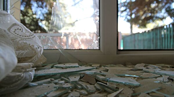 Разбитое окно дома, поврежденное разрывом снаряда в результате обстрела в Петровском районе Донецка