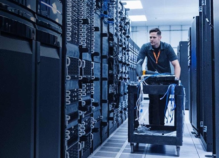 Man walking through a server room with a table full of cables