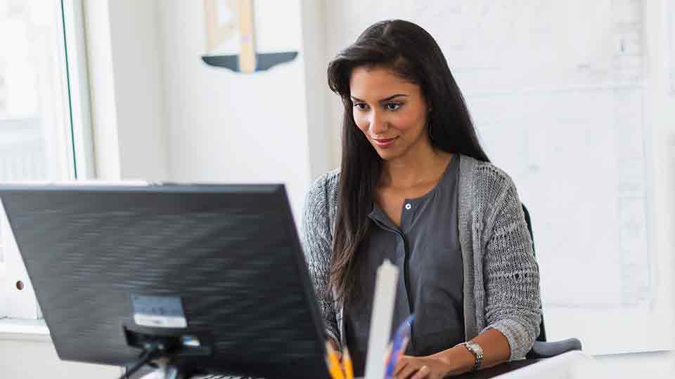 a smiling professional looks into a laptop computer