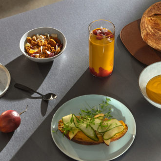 A table contains dishes filled with soup, bread and other foods.