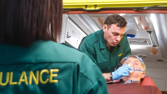 two medical people in ambulance helping a patient