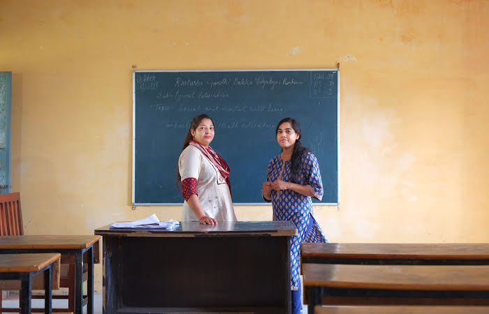 Two women standing near a chalkboard in a classroom