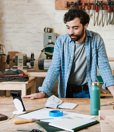 An image of a man looking at his Google Pixel phone in his woodworking shop
