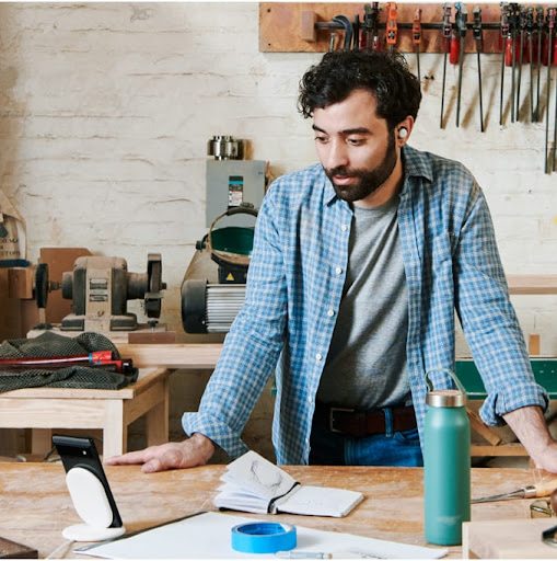 An image of a man looking at his Google Pixel phone in his woodworking shop
