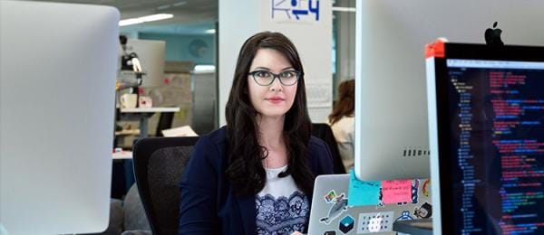 Woman holding laptop while leaning against table