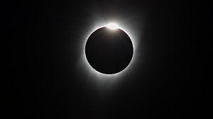 Black background with rays extending out from a circle and a bright light from the top of the circle.