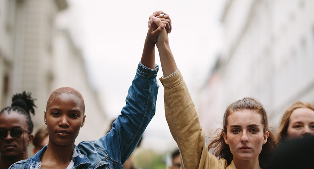 Group of activists with holding hands protesting in the city. Rebellions doing demonstration on the street holding hands.