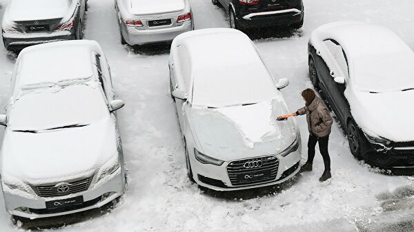 Девушка чистит автомобиль от снега