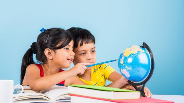 Young girl and boy studying a globe.