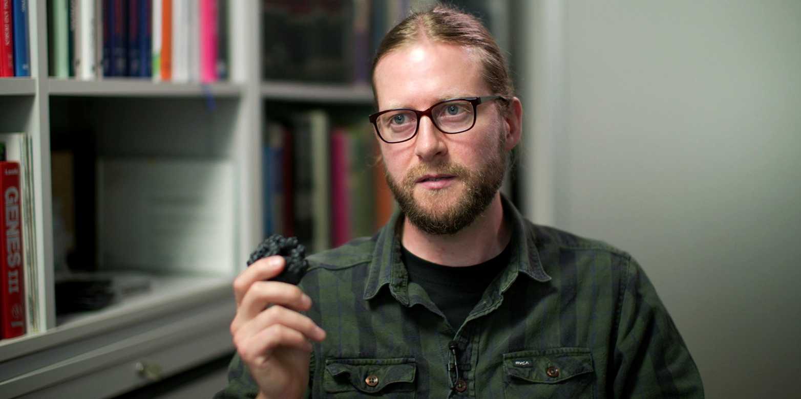 Tom Edwardson holding a model of his protein cage in his hand