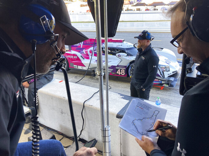 Jimmie Johnson, left, listens to crew chief Chad Knaus, Friday, Nov. 12, 2021, at Road Atlanta Raceway in Braselton, Georgia. Johnson and Knaus won a record-tying seven NASCAR championships together before their relationship fractured and they split in 2019 after 17 seasons together. The two have been reunited by work four times this season as Knaus has run a sports car team that Johnson and Hendrick Motorsports put together in partnership with Action Express in four IMSA endurance sports car races this year. Both say their relationship is currently in a good place. (AP Photo/Jenna Fryer)