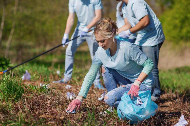 Woman picking up trash in a park.