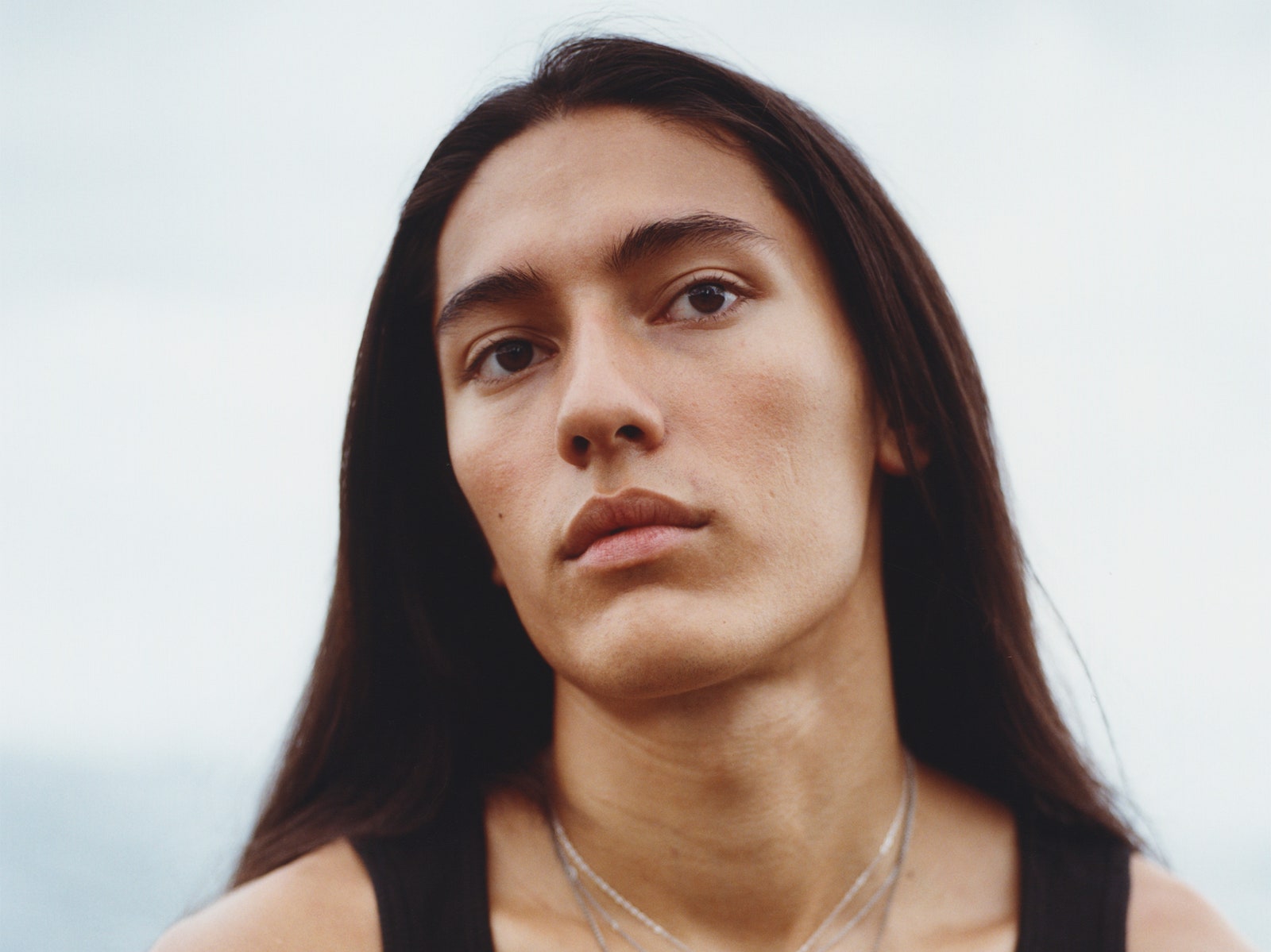 Cherokee Jack wearing silver charm necklaces and a black tank top that reads NASCAR