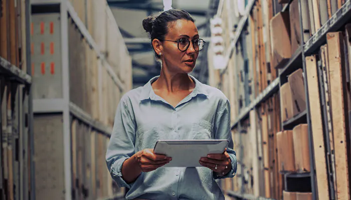 Femme avec une tablette dans une allée d'entrepôt