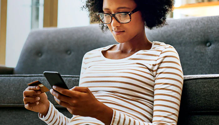 Femme tenant une carte de crédit et un téléphone