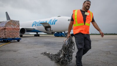 Abe Diaz of the Disaster Relief by Amazon team hauls cargo netting across the tarmac at Lynden Pindling International Airport in Nassau.