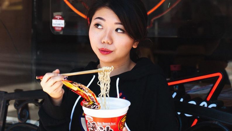 A woman stands eating food outside a restaurant