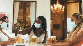 Three people having beer with facemasks on