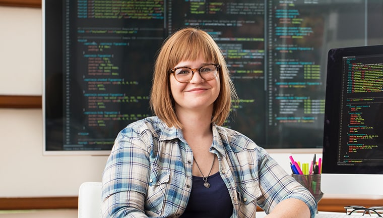 Woman sitting in-front of computers showing coding