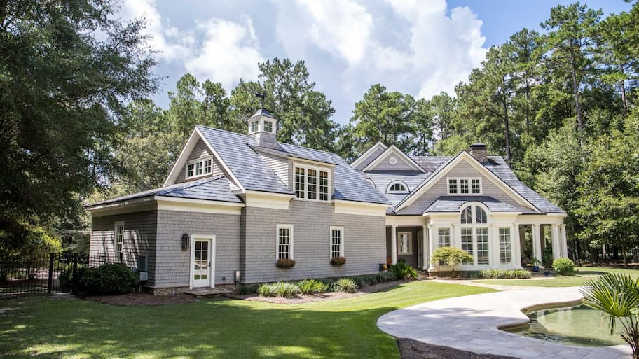 A large gray house with wood shingle and a chimne