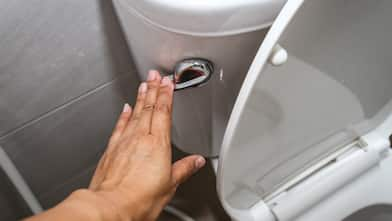 A woman holding down the toilet handle