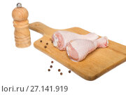 Two raw chicken drumsticks on a cutting board and peppermill on a white background. Стоковое фото, фотограф Юлия Бабкина / Фотобанк Лори