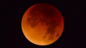 Image of Full Moon red in color due to refraction with dark sky in the background.