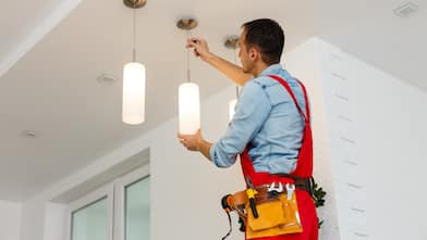 Electrician man worker installing ceiling lamp