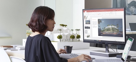 Women working on a computer sitting next to an architectural model