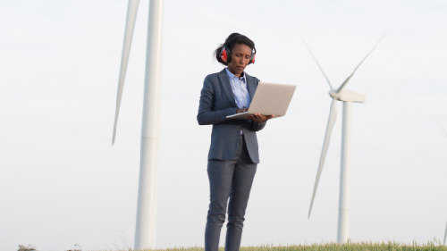 Woman working on the laptop computer at turbine field