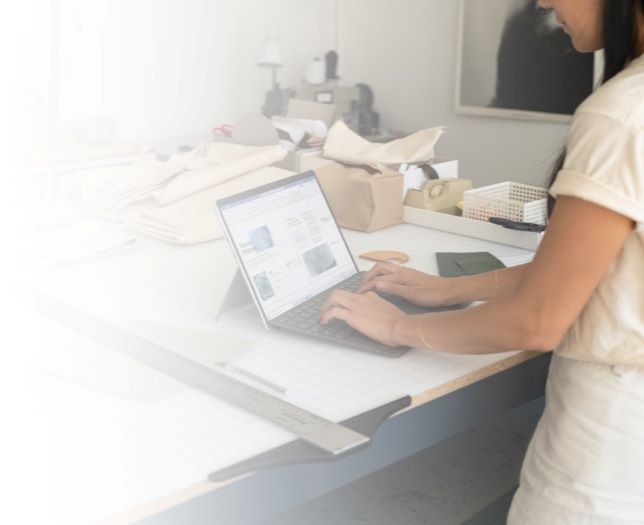 Person standing in a workshop typing on a laptop