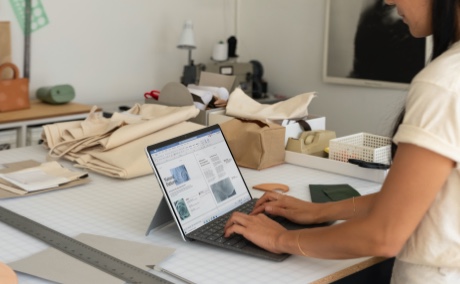 Person standing in a workshop typing on a laptop