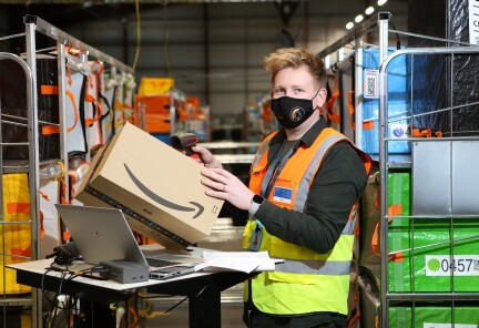 Dan White, Operations Supervisor at Amazon's delivery station in Penrith pictured wearing a high visibility vest and a face mask.