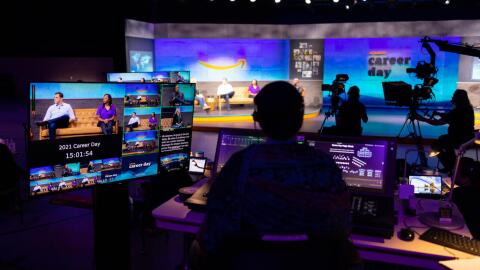 A person sitting behind a series of monitors works on Amazon Career day