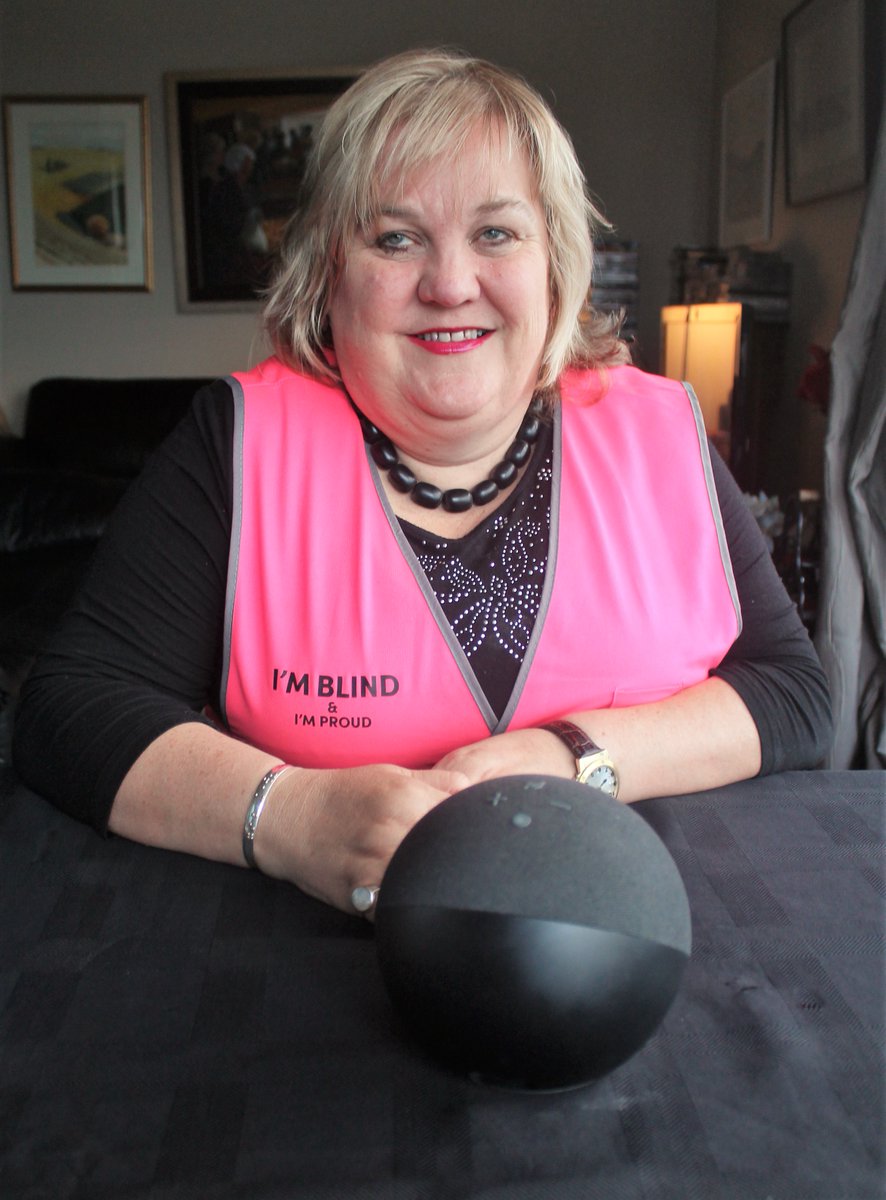 Julie, a customer from New Zealand, smiling and sitting with an Echo device in front of her.