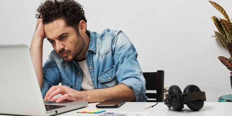 Tired and stressed businessman working with a laptop at home.