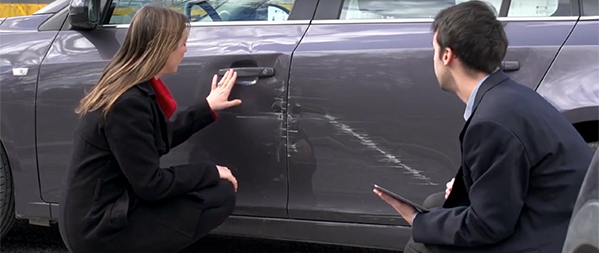 two people inspecting a car damaged