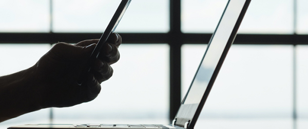 a man holding a smartphone in front of a laptop