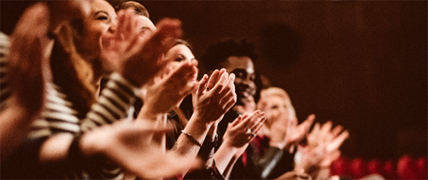 group of people clapping and smiling inside theather