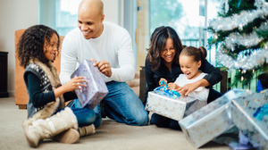 African american family opening presents under the christmas tree.