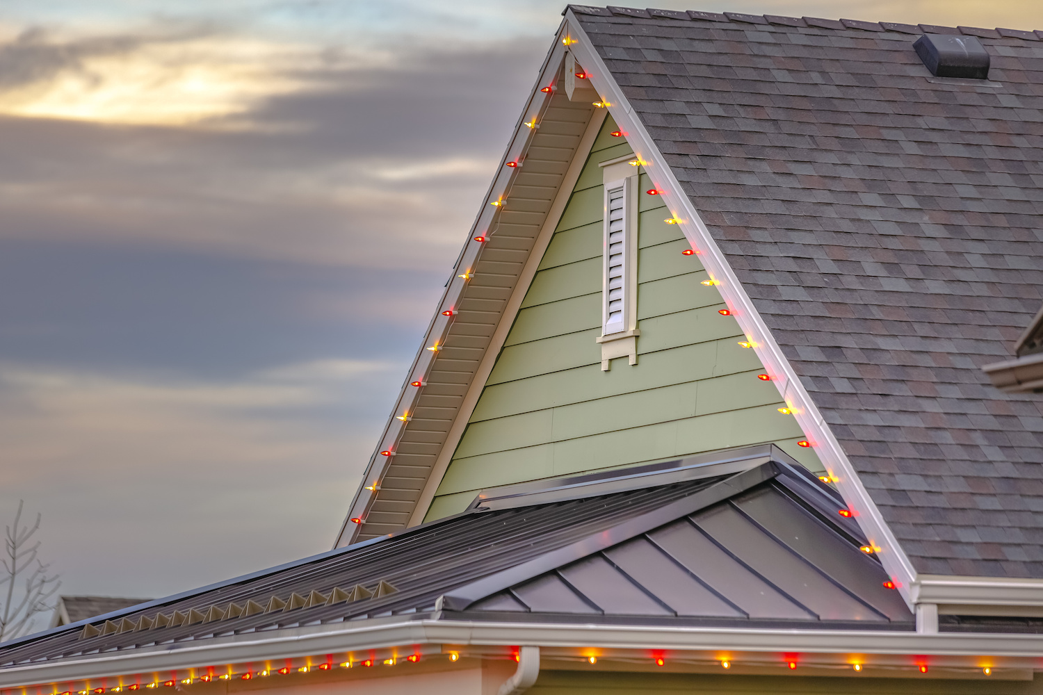 Red and yellow holiday lights decorate green house facade