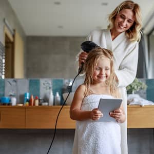 Mom using a hair dryer to dry daughter’s hair