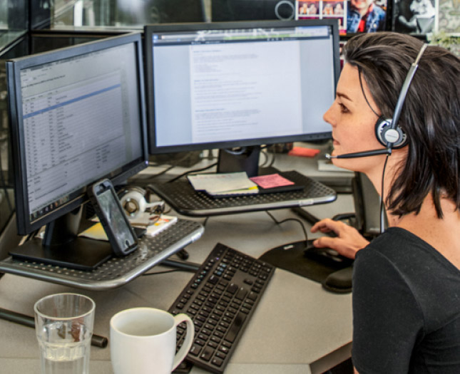 Business woman in front a computer with two monitors engaging on a call.