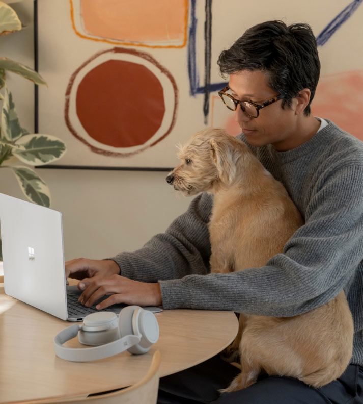 A man works from home with a dog in his lap