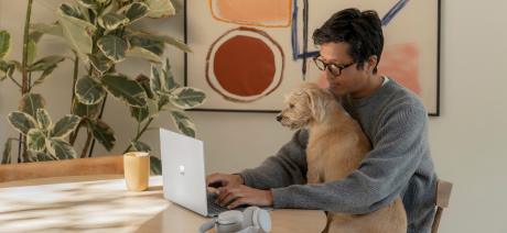 A man works from home with a dog in his lap
