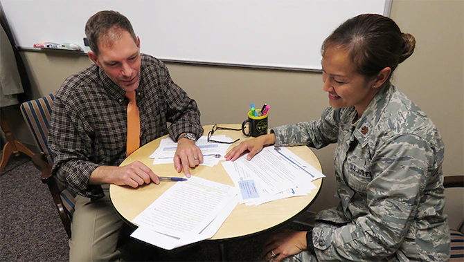 Male civilian staff member tutoring a female military officer