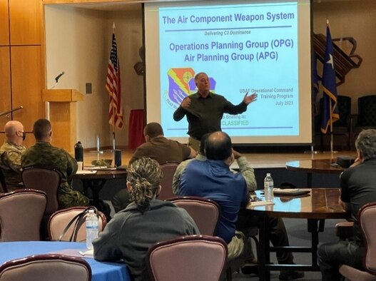 photo of man standing speaking to a group of U.S. Airmen