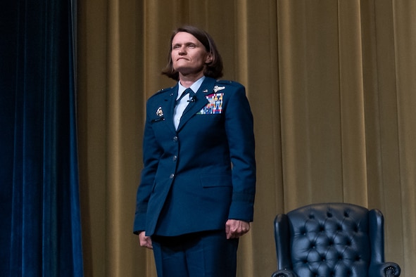 Brigadier Gen. Leslie Maher stands at attention on a stage during her assumption of command ceremony.