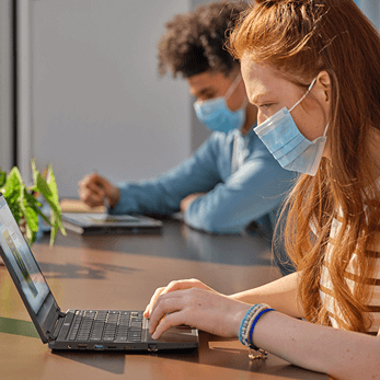 Woman wearing mask using a laptop.