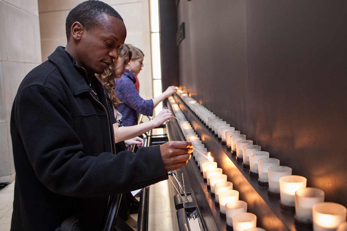 A Museum visitor lights a candle in the Museum Hall of Remembrance.